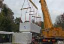 The first of the flats is lifted into place by a giant crane