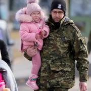 A Polish border guard carries a child as refugees from Ukraine cross into Poland at the Medyka crossing