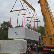 The first of the flats is lifted into place by a giant crane