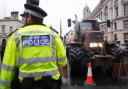 A police officer watches a tractor during a protest by farmers in central London over the changes to inheritance tax (James Manning/PA)