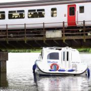 Trains travel slowly over the bridge where the Alpha Craft holiday boat is jammed underneath near the Rushcutters pub on Yarmouth Road. Picture: DENISE BRADLEY