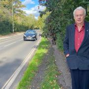 John Peacock, spokesman for the Norwich branch of UK-wide Living Streets charity, next to an overgrown section of the Bluebell Road footpath in Norwich